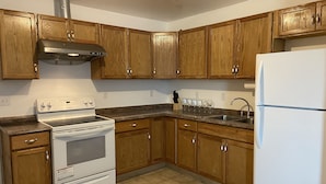 Une cuisine avec des meubles en bois, une hotte en acier inoxydable, une cuisinière blanche, un évier et un réfrigérateur.