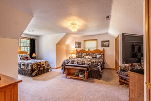 Une chambre avec deux lits, un ventilateur de plafond, une télévision et un banc en bois.