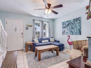 A living room with a blue sofa, wooden coffee table, and a ceiling fan.