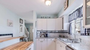 A kitchen with white cabinets, a wooden countertop, a coffee machine, and a sign that says 'BEACH'. - G & J Paradise (Rockport)