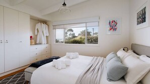 Een slaapkamer met een groot bed, een kledingkast, een raam met uitzicht en een hangende kapstok.