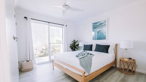Et soveværelse med seng, ventilator, et vindue og en plante.