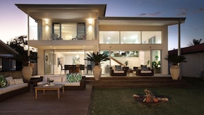 A modern two-story house with a patio, outdoor seating, and a fire pit. - 'Atra' - Jervis Bay Beach Front Holiday Home (Callala Beach)
