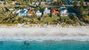 An aerial view of a coastal residential area with houses, a sandy beach, and clear blue waters. - 'Atra' - Jervis Bay Beach Front Holiday Home (Callala Beach)