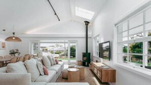 A modern living room with a sofa, TV, and large windows.