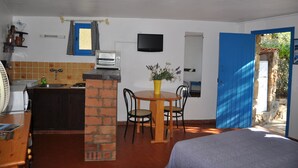 Una cocina compacta con tostadora, lavamanos y una puerta azul que da al exterior.