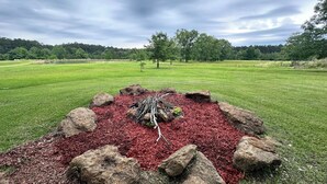 A landscaped area with a central mulched area surrounded by rocks and grass. - Camplee - 50 Acres of Freedom (Zavalla)