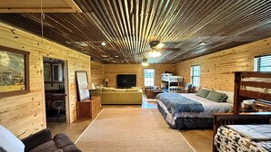 A cozy cabin interior with a wooden interior, a sofa, a bed, and a TV. - Camplee - 50 Acres of Freedom (Zavalla)