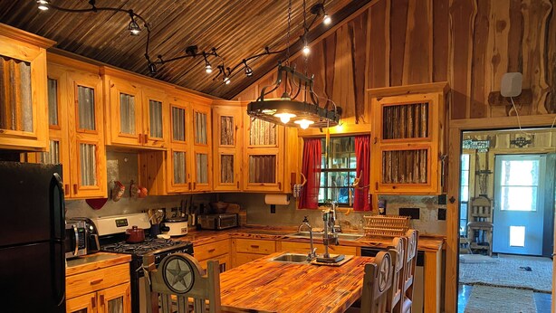 A rustic kitchen with wooden cabinets, a central island, and a stove. - Camplee - 50 Acres of Freedom (Zavalla)