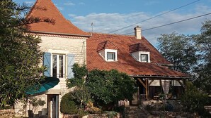 A two-story house with a steeply pitched roof, a stone facade, and a small balcony. - Rent this charming furnished studio near Rocamadour and Padirac  (Gramat)