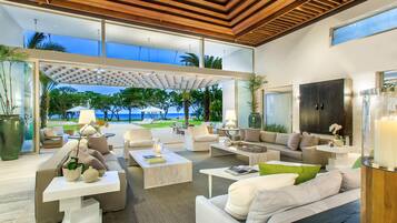 A modern living room with a view of the ocean, featuring a sofa, coffee tables, and a large cabinet.