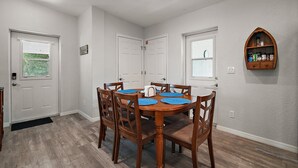 Un coin repas avec une table et des chaises en bois, des murs blancs et un buffet en bois accroché au mur.