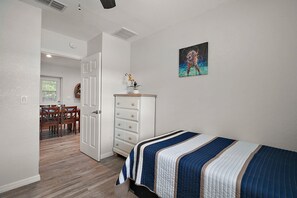 Um quarto com cama, penteadeira e um quadro na parede.