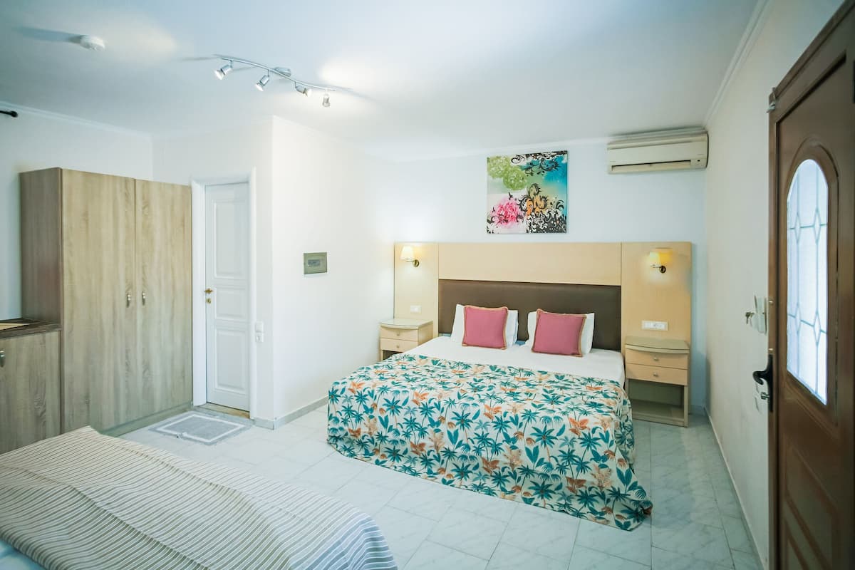 A bedroom with a bed, a wardrobe, a nightstand, and a wall-mounted air conditioner.