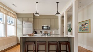 A kitchen with a central island, bar stools, a microwave, and a refrigerator.