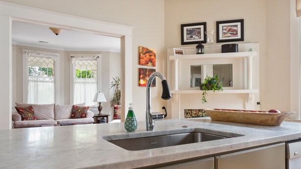 A kitchen with a sink, countertop, and a dining area with a sofa and a coffee table.