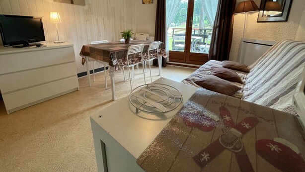 Un salon confortable avec un canapé, une table basse et un téléviseur. Il y a également un coin repas avec une table et des chaises.
