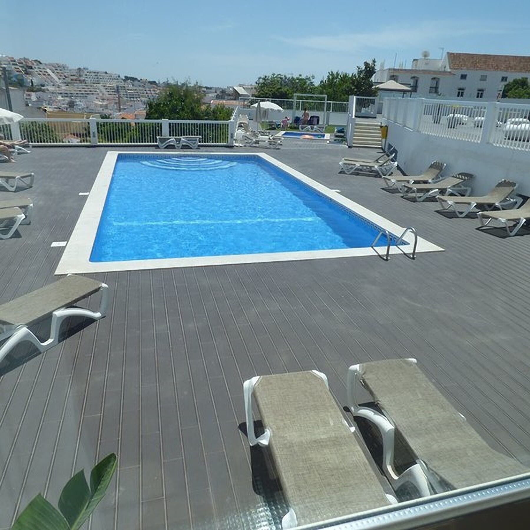 Une piscine sur le toit, avec une eau d’un bleu limpide, entourée de chaises longues et offrant une vue sur la ville.