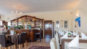 Un restaurante con zona de bar, muebles de madera y alfombra estampada.
