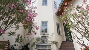 Un patio con una fuente, un banco y un edificio con techo de tejas.