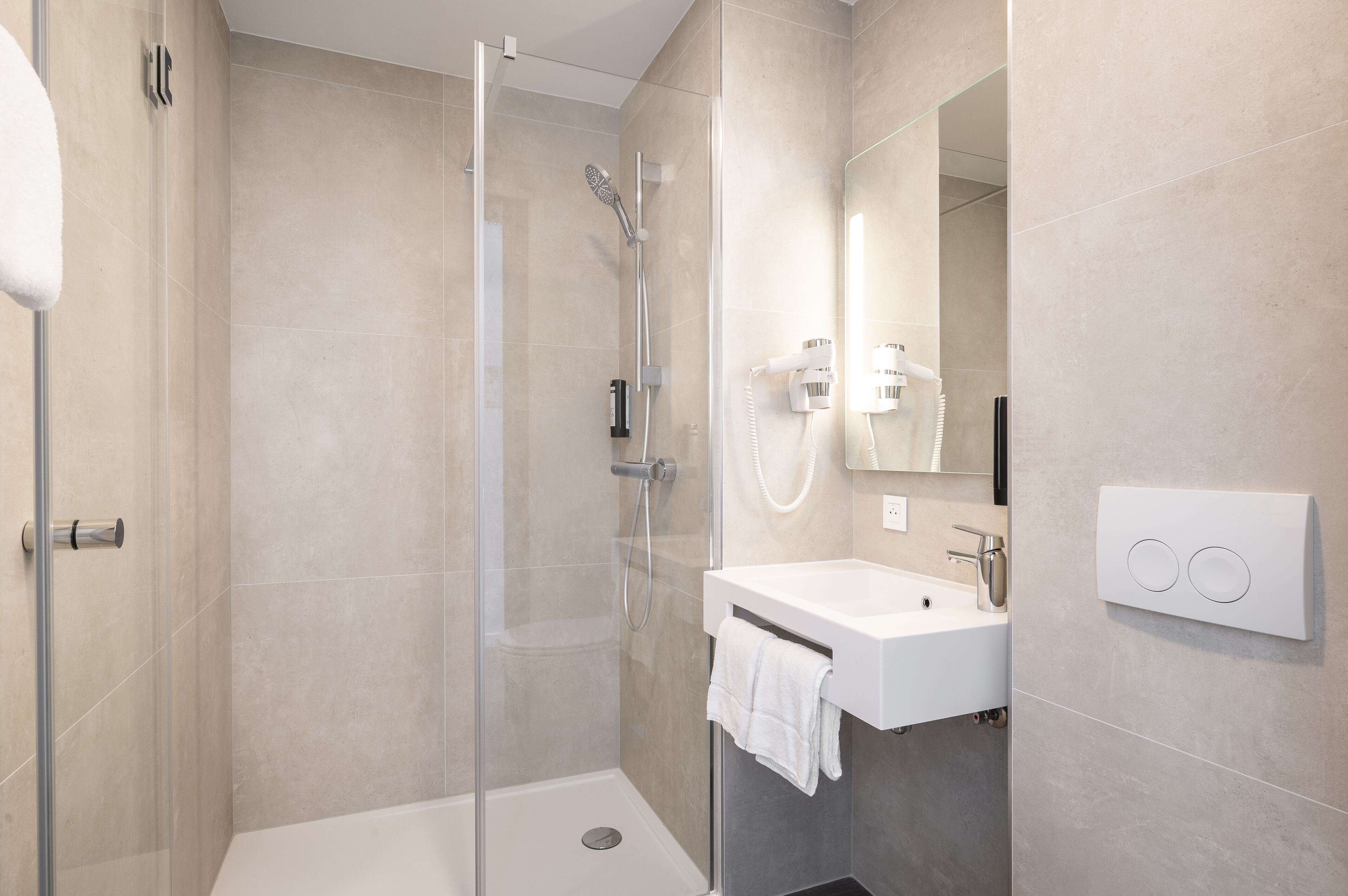 A modern bathroom with a glass shower enclosure, a white sink, and a mirror.