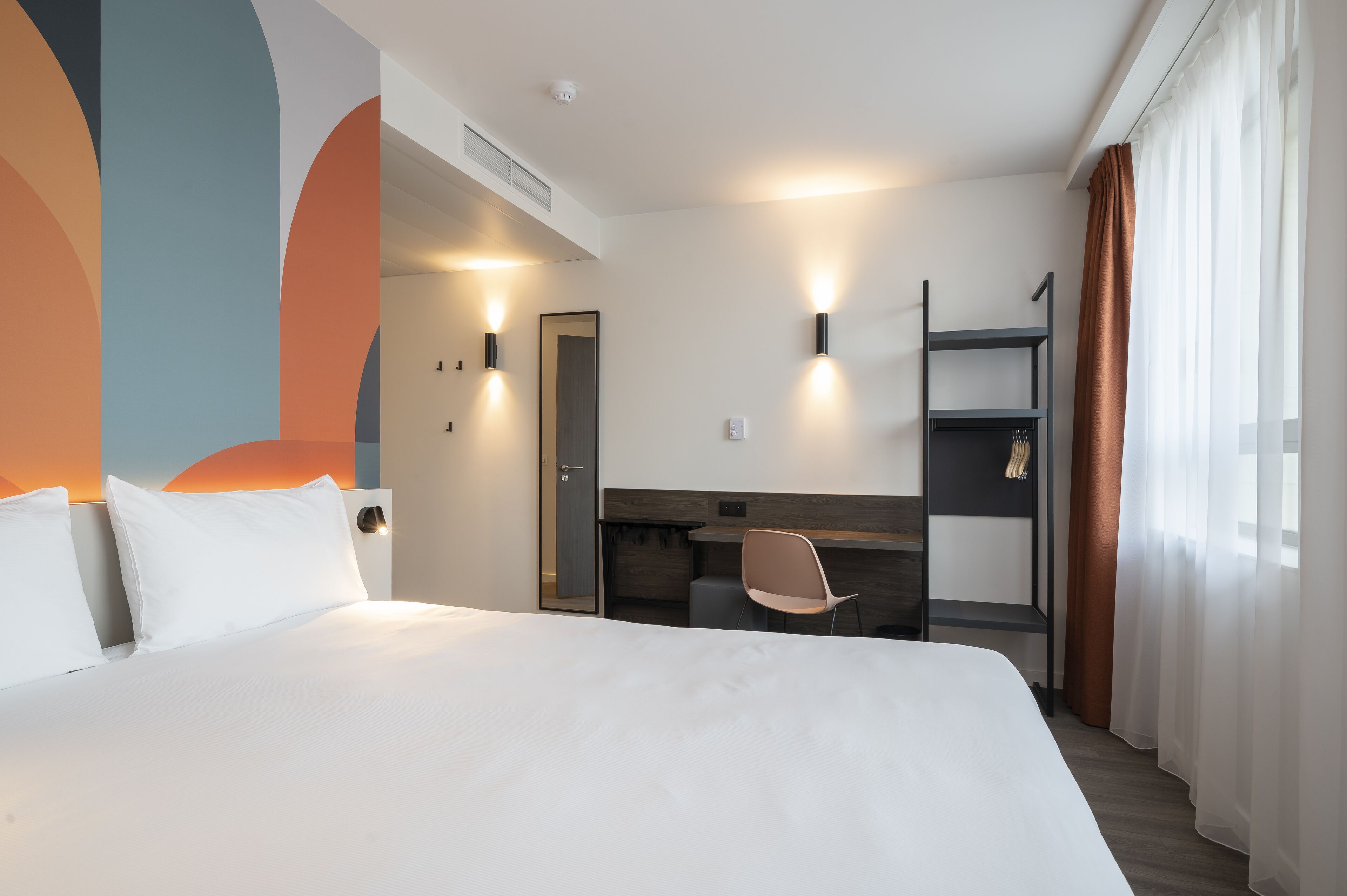 Ett hotellrum med en stor säng, ett skrivbord, en stol och en garderob.