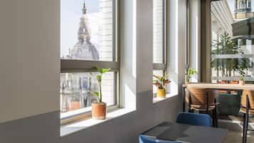 A modern interior with a large window, a table, chairs, and potted plants.