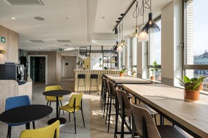 Un área de cocina moderna con una encimera larga, taburetes de bar y plantas en macetas.