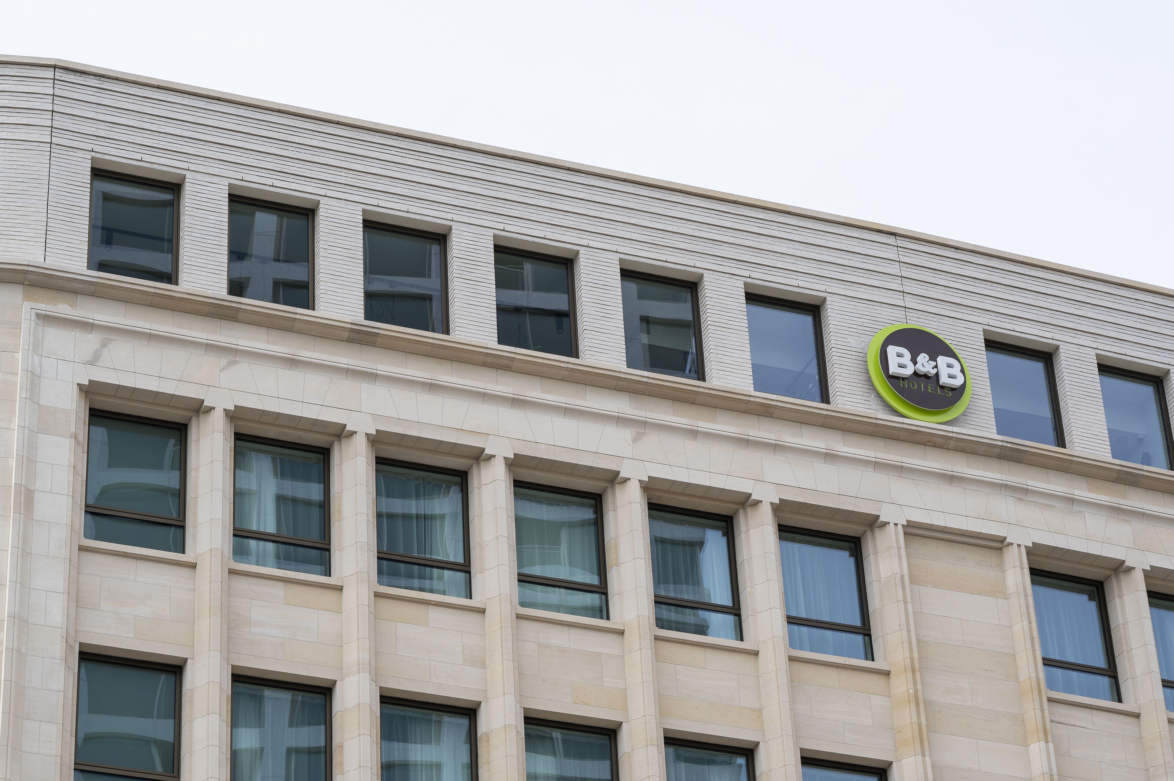 A hotel with a modern facade, featuring a prominent B&B logo on the upper level.