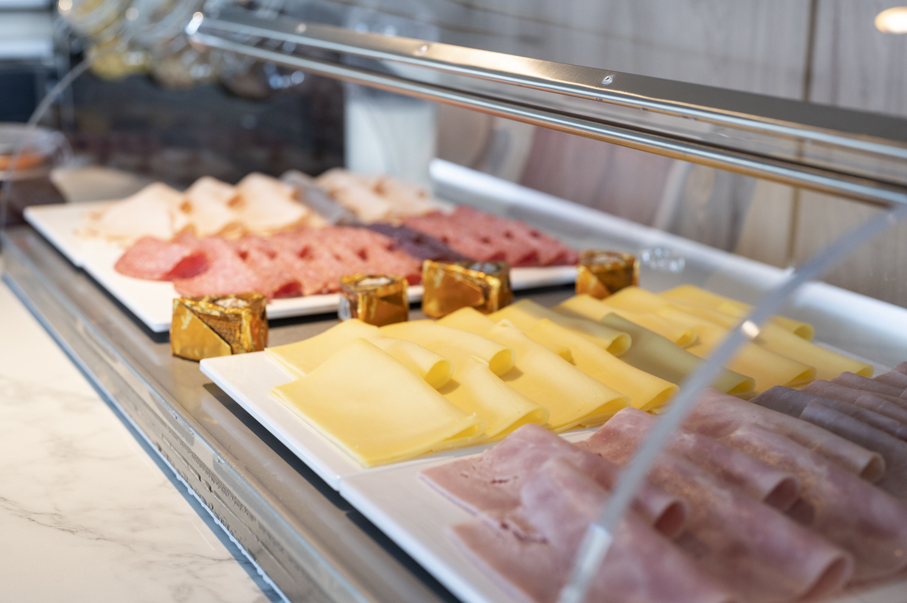 A deli counter with various meats and cheeses displayed behind a glass case.