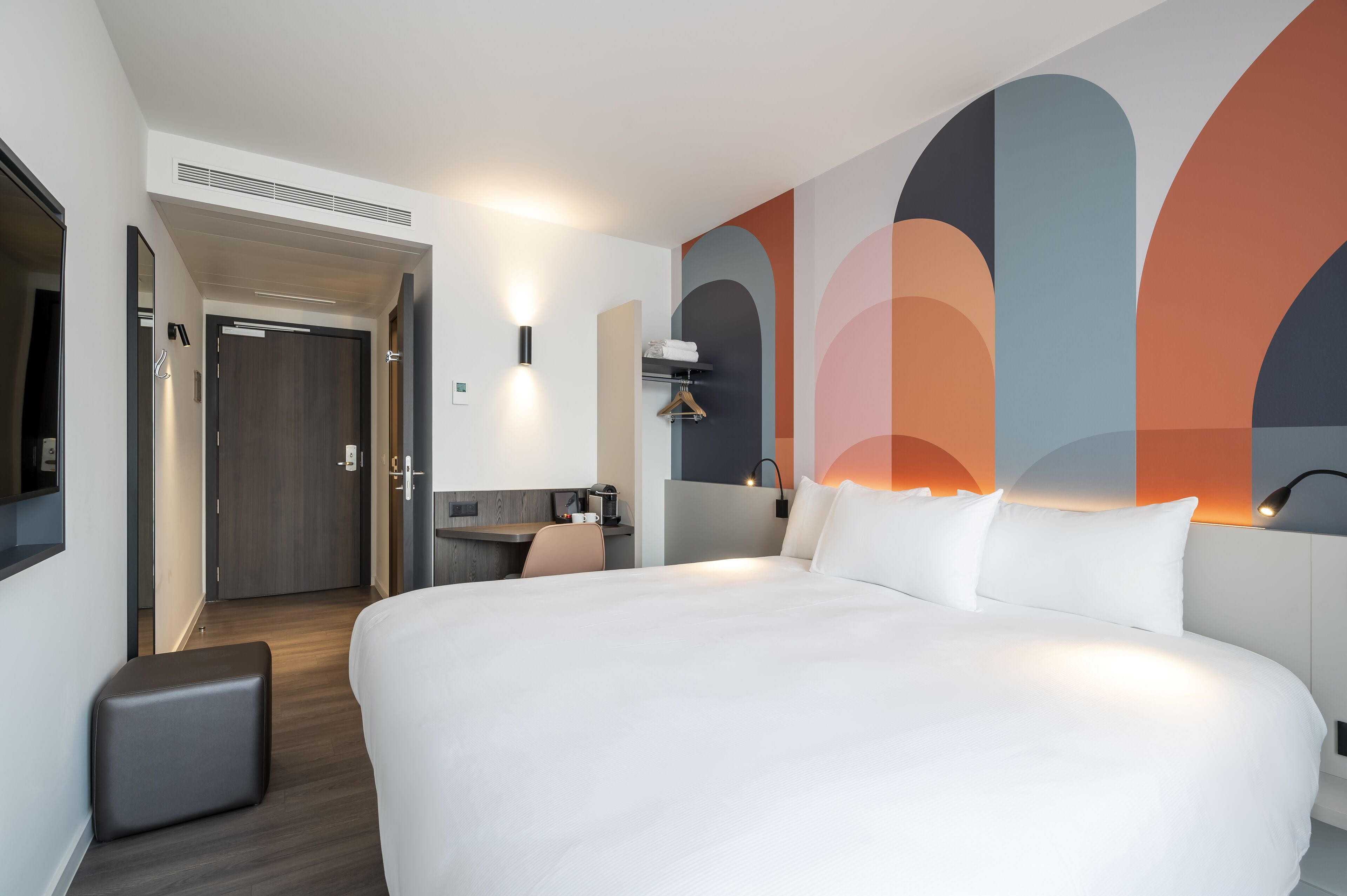 Una habitación de hotel moderna con una cama grande, un escritorio y una zona de estar.