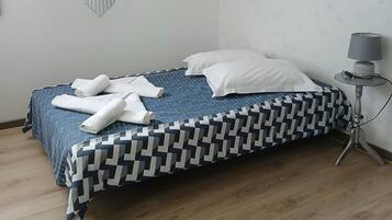 A bedroom with a bed, a bedside table with a lamp, and wall art.