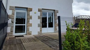 Een modern huis met een witte gevel, stenen details en een houten terras.