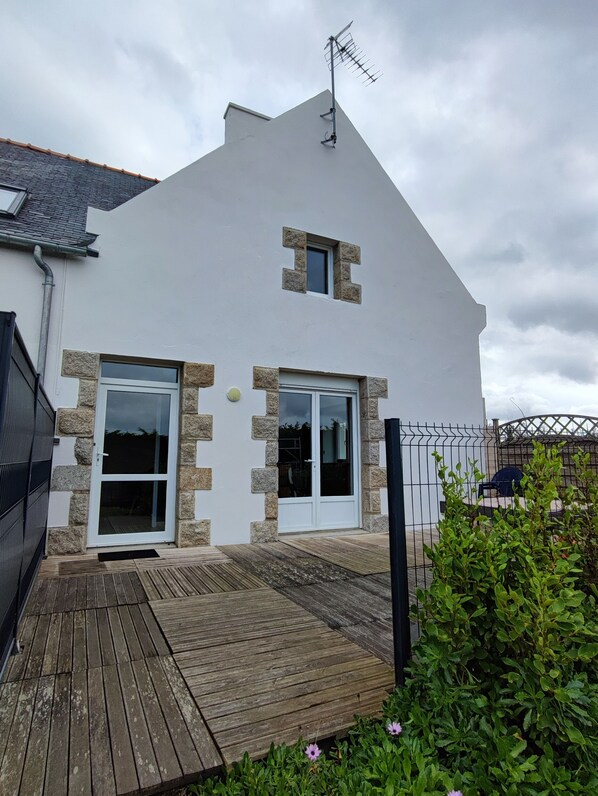Une maison moderne à l’extérieur blanc, agrémentée de touches de pierre et dotée d’une terrasse en bois.