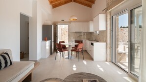A modern kitchen with a dining area, featuring a wooden ceiling, large windows, and a stone wall. - Evaero Villa II, Family Retreat with a 32m² Pool (Prinos)