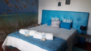 Una camera da letto con un letto grande, una testiera blu e un affresco che raffigura una spiaggia.