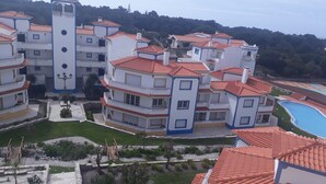 Un hotel a più piani con piscina, balconi a terrazza e una struttura a torre.