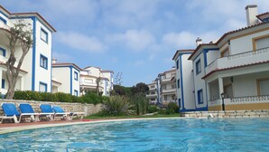 Una piscina con lettini e una parete in pietra.