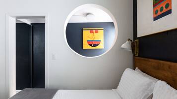 A bedroom with a bed, a circular wall art piece, a door, and a painting on the wall.