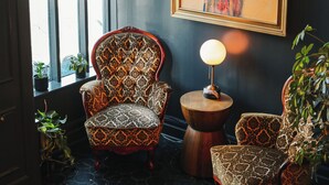 A room with patterned chairs, a round table with a lamp, and a large abstract painting on the wall. - The Metro Hotel (San Francisco)