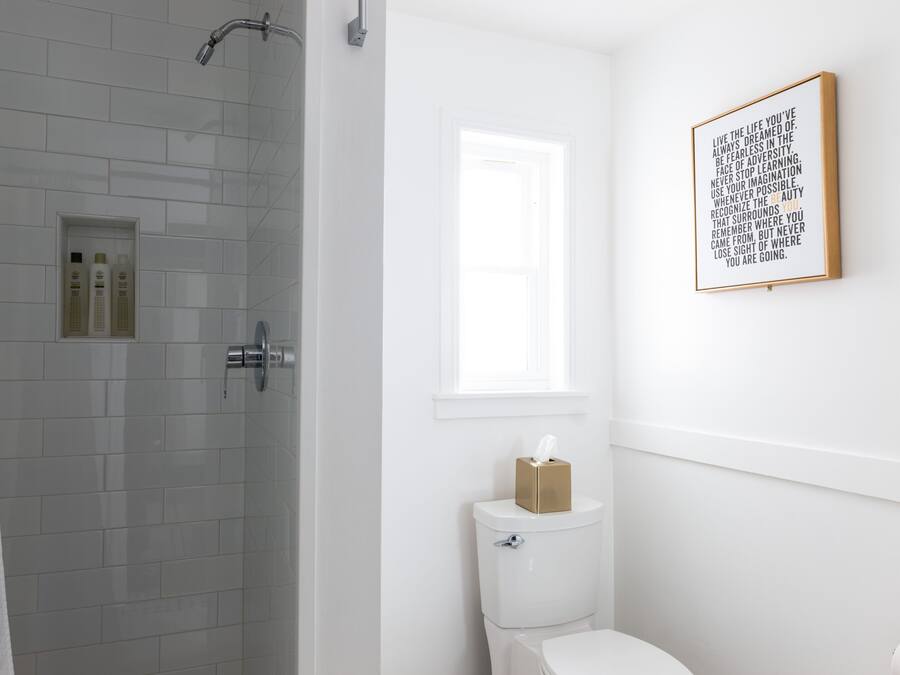 A bathroom with a shower, toilet, and a framed inspirational quote on the wall.