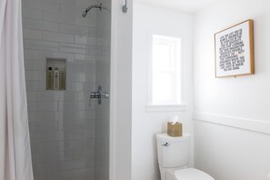 Une salle de bain avec douche, toilettes et une citation inspirante encadrée au mur.