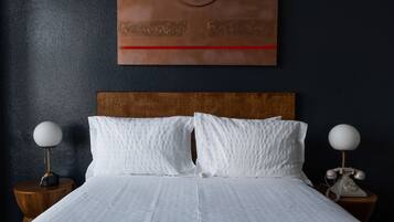 A neatly made bed with white bedding, two bedside tables with lamps, and a wall art piece above the bed.