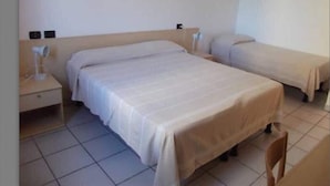 Een hotelkamer met twee eenpersoonsbedden, een nachtkastje met een lamp en een stoel.