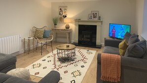 A living room with a fireplace, a television, a sofa, a coffee table, and a patterned rug. - Farm House - Sleeps 7 - Garden - Parking (Kinsale)