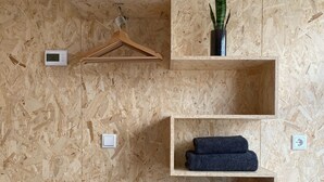 A room with a wooden wall, a thermostat, a plant, and shelves with folded towels. - Houseboat with private studio near downtown and Rai in the middle of urban greenery (Amsterdam)