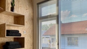 A bedroom with a large window, wooden shelving, and a bed with a brown cover. - Houseboat with private studio near downtown and Rai in the middle of urban greenery (Amsterdam)