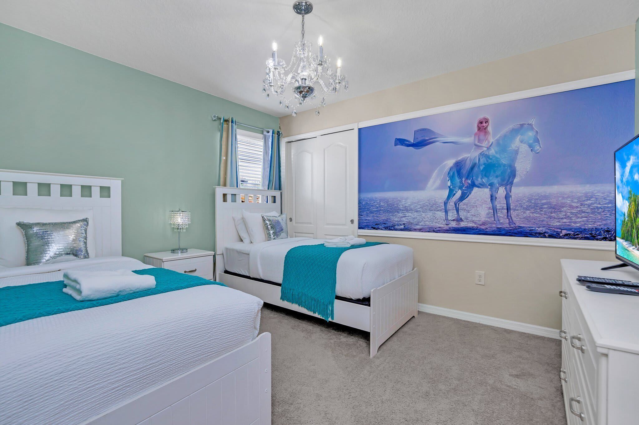A bedroom with two beds, a chandelier, a large window, and a painting of a horse.