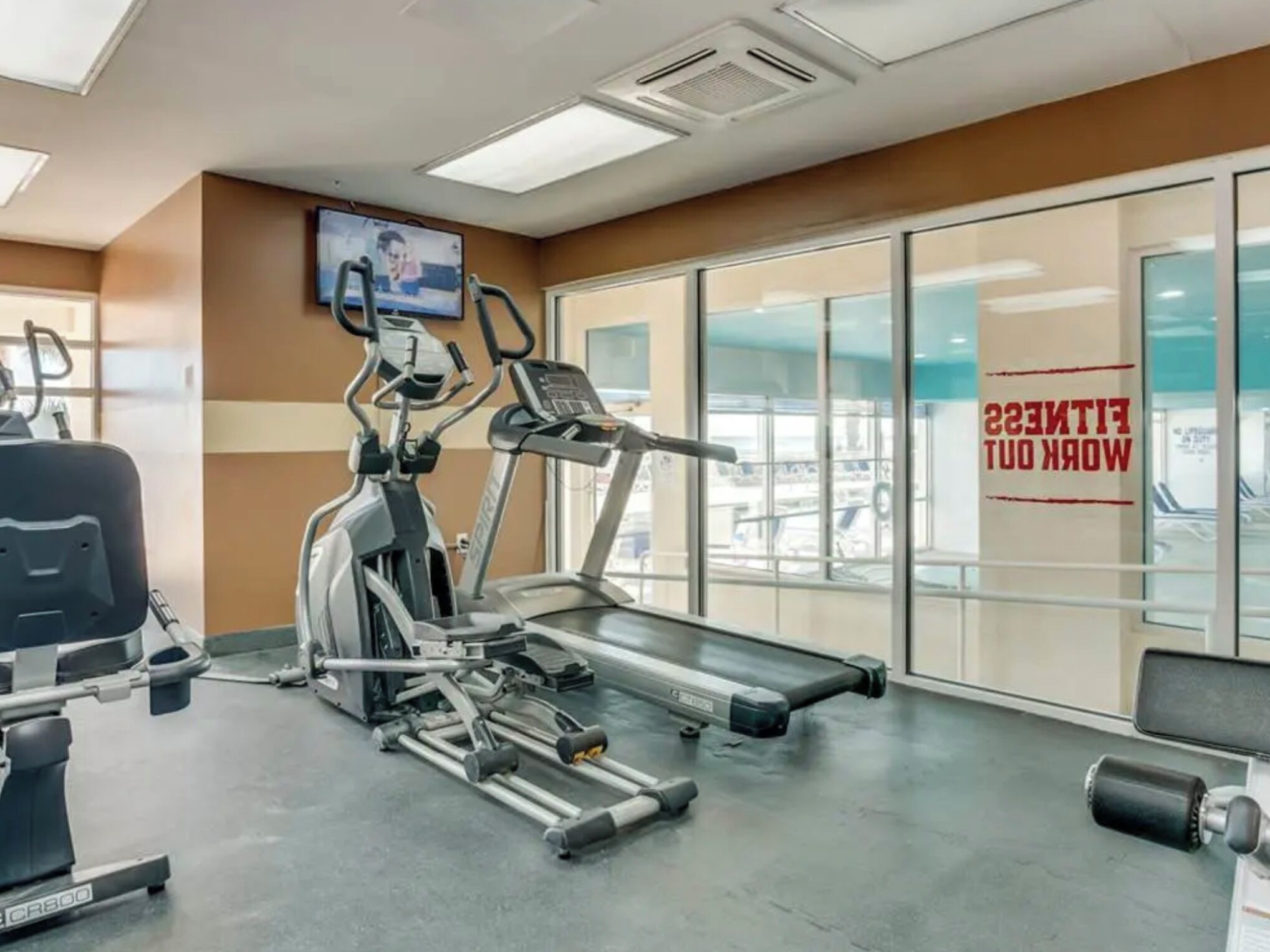 A gym with treadmills, elliptical machines, and weight benches.