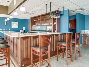 A bar area with a marble countertop, wooden bar stools, and a shelf with bottles and glasses. - Bay Watch 333-2BR/2BA Oceanfront Condo in North Myrtle Beach (North Myrtle Beach)